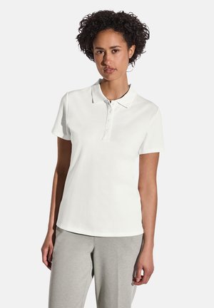 Hvid bomulds polo t-shirt med korte ærmer og en tre-knaps lukning; parret med lysegrå sweatpants. Ingen synlige mønstre eller accenter.