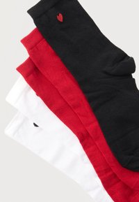 Τρία ζευγάρια διπλωμένες κάλτσες σε μαύρο, κόκκινο και άσπρο χρώμα, με μικρά σχέδια καρδιάς κοντά στην κορυφή.