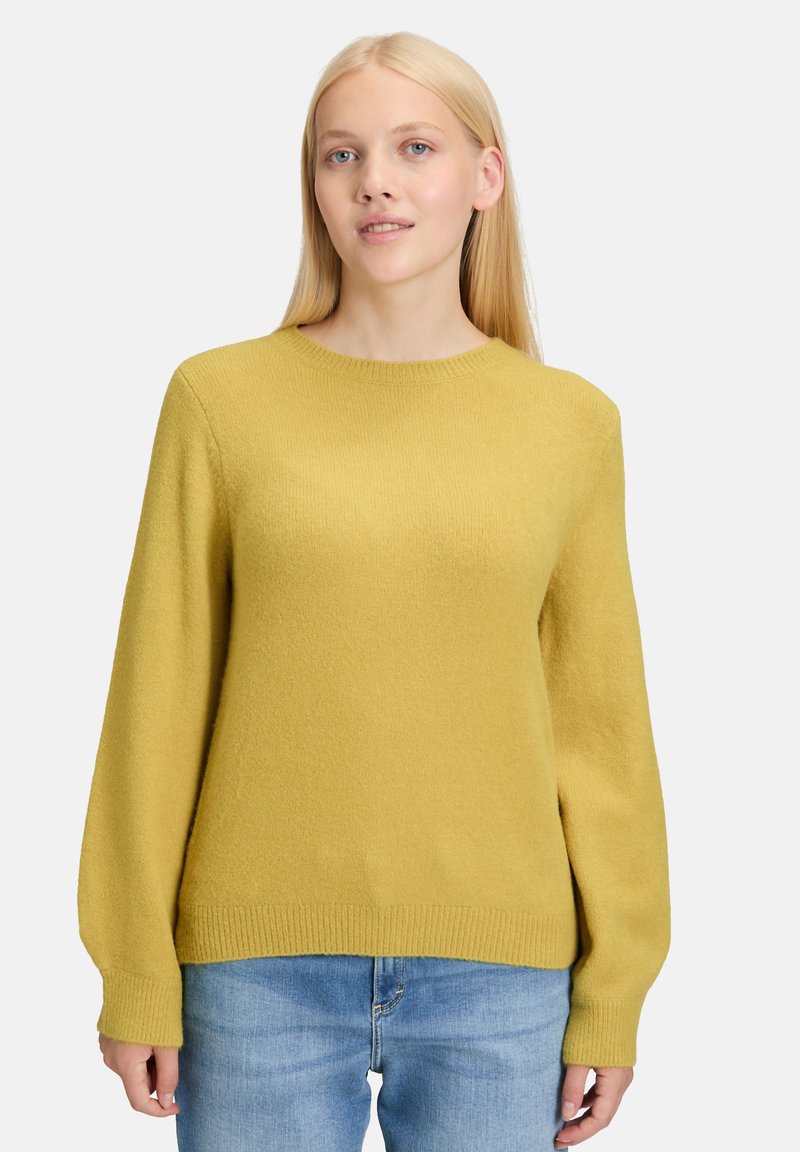 Senfgelber Pullover mit rundem Halsausschnitt, gerippten Bündchen und Saum, aus weichem, strukturiertem Stoff, kombiniert mit hellblauen Jeans.