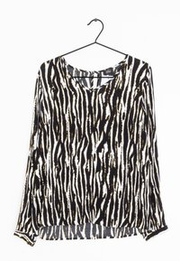 Blusa a maniche lunghe con scollatura a V in un motivo a righe zebra bianco e nero; il tessuto sembra morbido con una consistenza leggera.