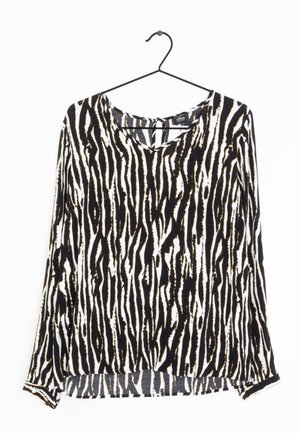 Long-sleeve blouse with a V-neck in a black and white zebra stripe pattern; fabric appears soft with a lightweight texture.