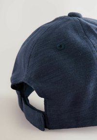 Marineblauwe pet van gestructureerde stof, met een gestikte klep, een verstelbare band aan de achterkant en een ventilatiegaatje.