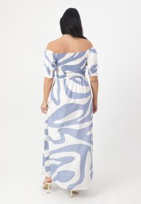 Maxi abito scollato in azzurro chiaro e bianco con motivi astratti. Presenta un corpetto arricciato e maniche a sbuffo in tessuto leggero.