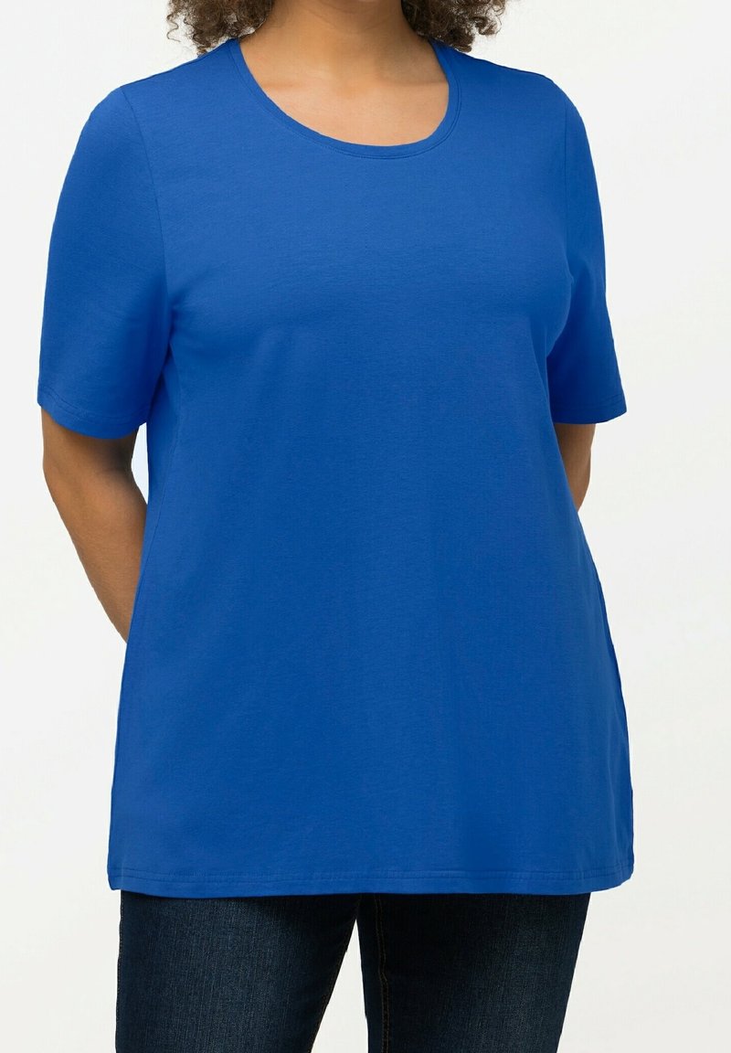 T-shirt bleu à manches courtes avec un col rond, fabriqué en tissu coton doux. Présente une coupe décontractée et un ourlet droit. Porté avec un jean foncé.