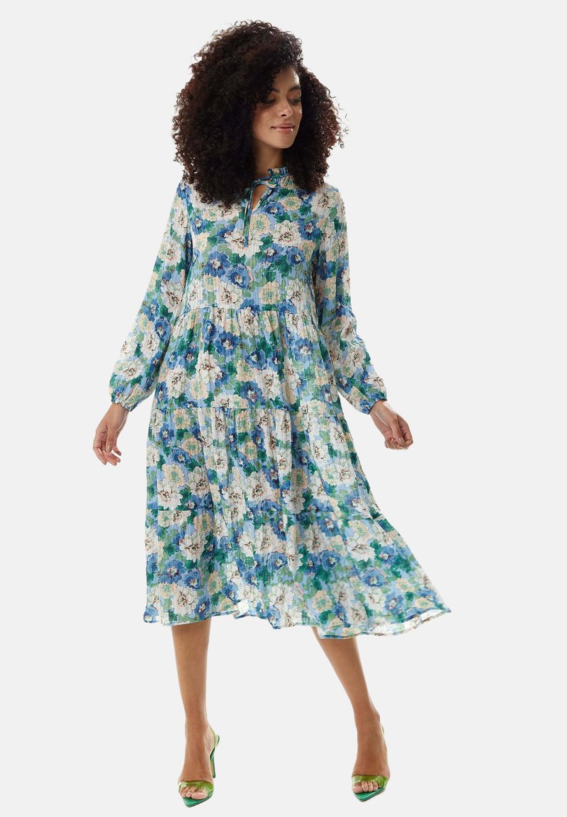 Floral midi dress with long sleeves, featuring a green and blue pattern, lightweight fabric, and a tie neckline; flowy silhouette.