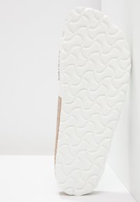 Witte rubberen schoenzool met een getextureerd golfpatroon, met een natuurlijk bruin kurkachtig materiaal langs de rand. Schoon en minimalistisch ontwerp.