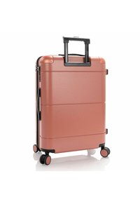 Rose gold hard-shell suitcase with a textured surface, retractable handle, four black wheels, and a sleek rectangular design.