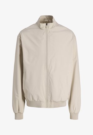 Giacca beige con zip, collo alla coreana, maniche lunghe, polsini elasticizzati e vita elasticizzata, mostrata su sfondo bianco.