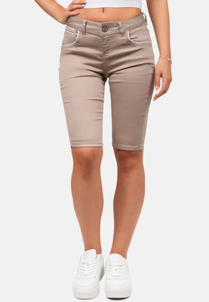 Shorts en denim beige à coupe slim, avec des coutures blanches sur les poches et une texture lisse, associés à des baskets blanches.