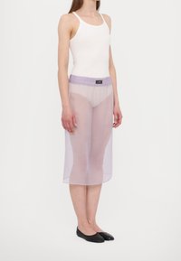 Läpinäkyvä purppurainen midi-hame, jossa on joustava vyötärö ja logoyksityiskohta, kerrostettuna yhteensopivan aluskerroksen päälle, yhdistettynä mustiin tasapohjaisiin kenkiin.