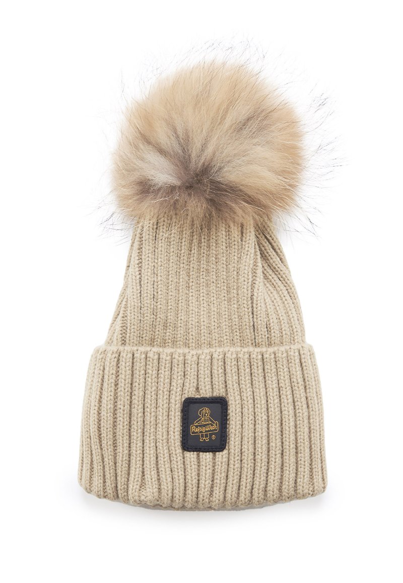 Cappello lavorato a maglia beige con una texture a coste, sormontato da un grande pompon in pelliccia sintetica. Presenta un'etichetta quadrata nera con dettagli del logo in oro.