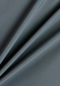 Tejido gris suave y liso plegado con suaves pliegues, mostrando una fina textura y un acabado mate con una iluminación uniforme.