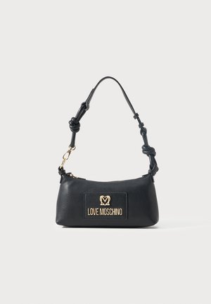 Sac à main Moschino noir avec plaque logo dorée, bandoulière en cuir nouée et fermeture éclair sur fond blanc.