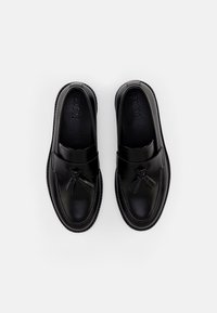 Mocassins en cuir noir avec une finition lisse, un accent à pampilles et un design à bout rond avec des coutures contrastantes sur la semelle.
