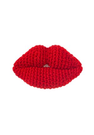 Jasnoczerwony dziergany przedmiot w kształcie ust na białym tle.