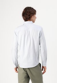 Camisa de manga larga a rayas azul claro con cuello y puños abotonados, fabricada en tejido transpirable, con un dobladillo redondeado para un ajuste relajado.