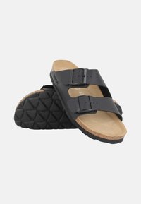 Black slide sandals with two adjustable straps, a cork footbed, and a textured rubber outsole featuring a diamond pattern.