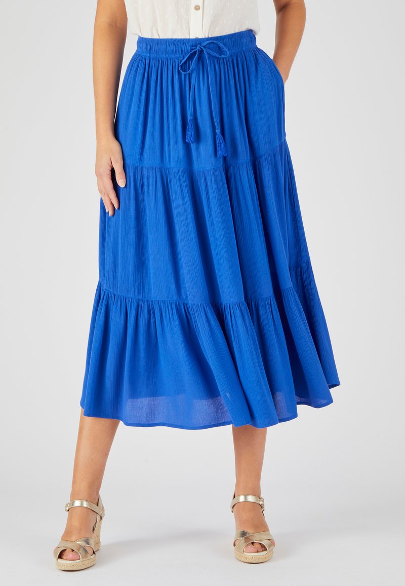 Falda azul con volantes y cintura con cordón ajustable, adornos de borlas. Hecha de un tejido ligero, presenta una silueta fluida y una superficie texturizada.