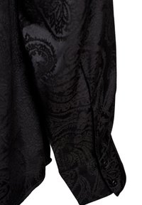 Maglietta nera a maniche lunghe con motivo paisley, caratterizzata da una texture morbida e polsini con bottoni. Il tessuto leggermente testurizzato aggiunge profondità.