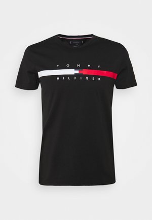 Schwarzes kurzärmeliges T-Shirt mit horizontalem weißen, grauen und roten Streifen über der Brust und dem Text "Tommy Hilfiger" über und unter dem Streifen.
