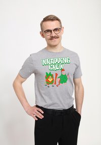Szara koszulka z grafiką "WRAPPING CREW" przedstawiającą postacie z kreskówek, nadrukowaną na zielono. Koszulka ma okrągły dekolt i krótkie rękawy.