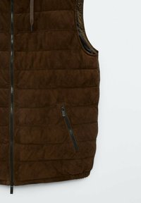 Veste sans manches matelassée marron foncé avec fermeture éclair à l'avant et poche zippée diagonale sur le côté droit.