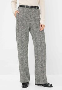 Grijs houndstooth-patroon broek met een hoge taille, voorzien van zijzakken en een zwarte riem, gedragen met een lichtgekleurde geribde trui.