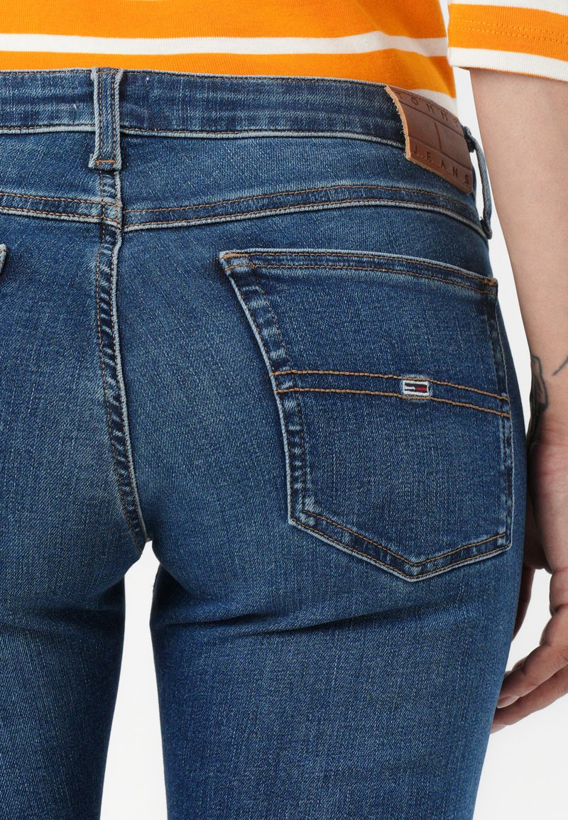 Navy niebieskie dżinsy o dopasowanym kroju, z dwiema tylnymi kieszeniami i brązową skórzaną metką marki w talii. Szczegóły w kontrastowym ściegu.