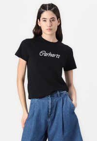 Černé triko s krátkým rukávem se strukturovaným bílým logem "Carhartt" na přední straně, zkombinované s vyššími modrými džínovými kalhotami.