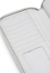 Interno di un portafoglio bianco con cerniera, dotato di molte tasche per carte, una tasca trasparente per documenti d'identità e una texture di tessuto liscia. Accentuato da una cerniera con perline.
