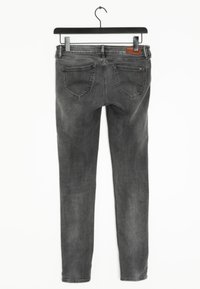 Vaqueros de denim gris con un diseño ajustado, que presentan una cinturilla plana, dos bolsillos traseros y una etiqueta de cuero de la marca en la cintura.