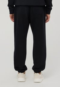 Pantaloni sportivi neri realizzati in tessuto morbido, con vita e polsini elasticizzati, una tasca posteriore singola e una vestibilità comoda.