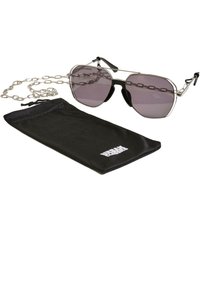 Sunglasses with a silver metal frame, grey lenses, a chain, and a black cloth pouch with a logo. The lenses have a slight gradient.
