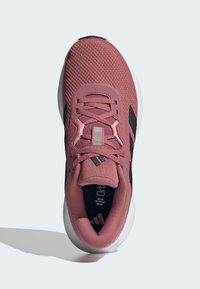 Pink athletic shoe with a mesh upper, black accents, and a white sole. Features a padded collar, textured laces, and a logo on the tongue.