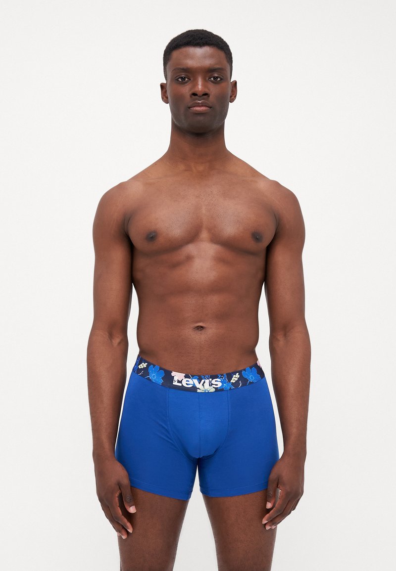 Boxers de algodón azules con una cinturilla de estampado floral que presenta el nombre de la marca. El diseño incluye una forma ajustada y una textura suave.