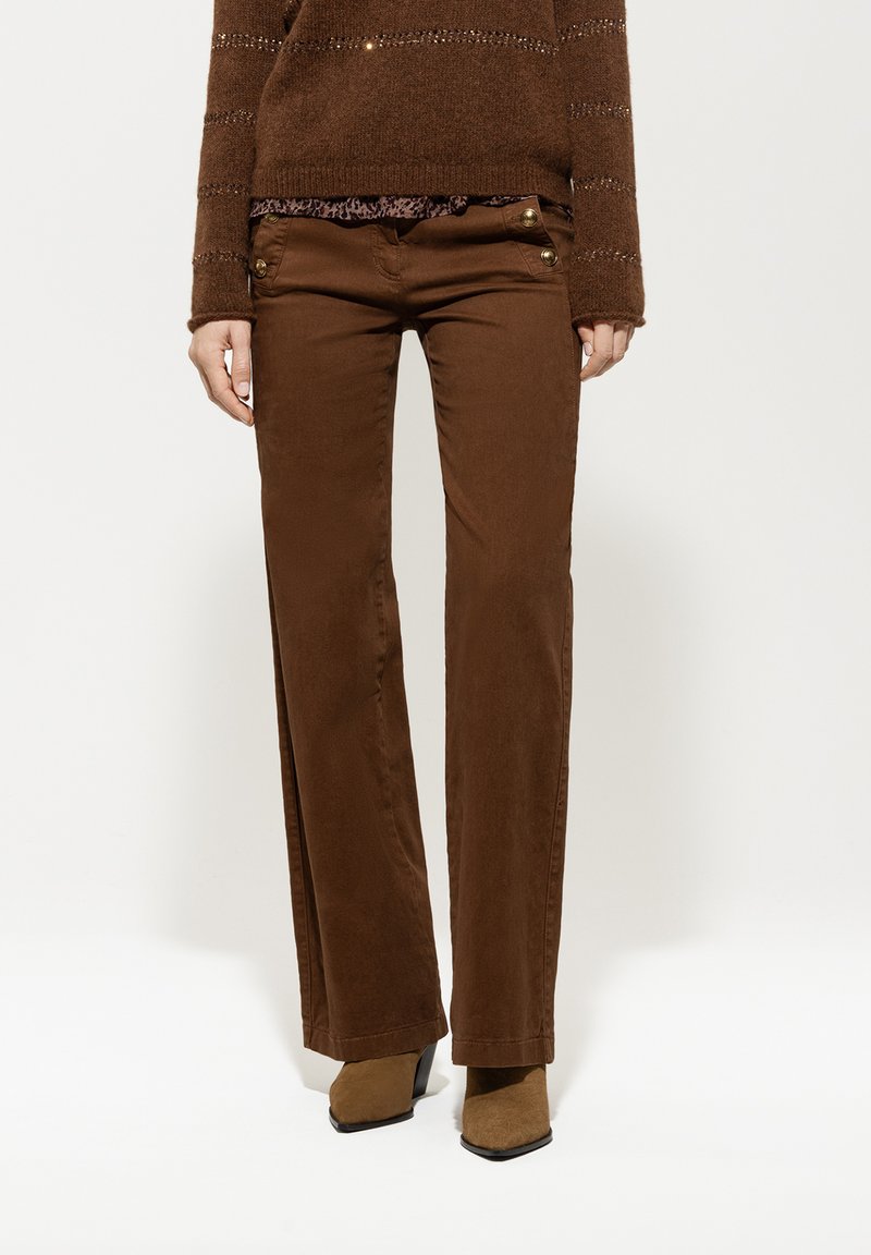 Brown, straight-leg pants with a smooth texture and decorative gold hardware at the pockets. Paired with a brown knit sweater.
