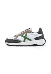 Zapatilla blanca con acentos en gris y verde, que presenta una combinación de materiales lisos y de ante, cierre de cordones y una suela de tracción texturizada.