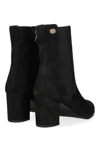 Botines de ante negros con tacón grueso, paneles laterales elásticos y un acento metálico en la parte trasera. Textura suave y diseño sencillo.