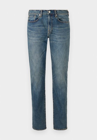 Jean en denim bleu avec une coupe droite, dotés d'une fermeture à bouton à l'avant, d'un style à cinq poches et d'un léger dégradé le long des cuisses.