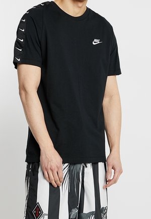 Black cotton t-shirt featuring short sleeves with white Nike logo on the chest and a unique lacing detail along the shoulder seams.