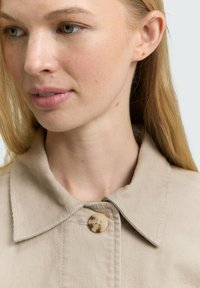 Light beige corduroy jacket with a classic collar, featuring a round button and subtle texture. The fabric has visible ribbing and stitching.