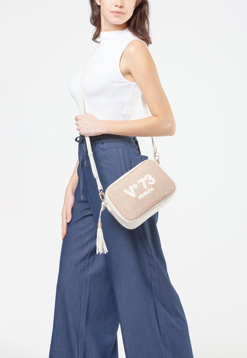 Borsa a tracolla intrecciata beige con accenti bianchi e chiusura con zip, dotata di fondo in ecopelle e un tassello decorativo.