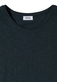 T-shirt vert foncé à col rond avec une étiquette en tissu cousue à l'intérieur de l'encolure portant l'inscription "CECIL" en lettres noires.