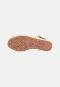 Sandal sole with a textured rubber material, featuring a floral pattern and a circular motif, colored in light brown with a reinforced edge.