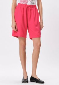 Różowe szorty do kolan wykonane z lekkiego materiału, z elastyczną talią wyposażoną w sznurek oraz bocznymi kieszeniami.