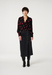 Black button-up blouse with red chili pepper pattern, paired with a high-waisted black denim skirt featuring a button-down front. Black knee-high boots.