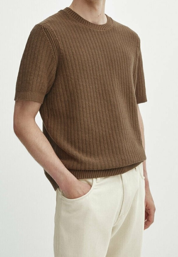 Brun, strikket kortærmet sweater med et tekstureret mønster, rund halsudskæring og afslappet pasform, parret med lyse bukser.