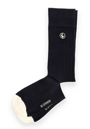 Par de calcetines negros de media caña con punteras color crema, el nombre de la marca en blanco y un pequeño logotipo circular blanco en el puño.