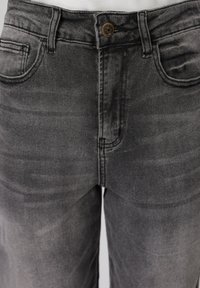 Γκρι τζιν από τζιν ύφασμα στη μέση και την πάνω περιοχή των μηρών, με μεταλλικό κουμπί, ορατές εμπρός τσέπες και θηλιές για ζώνη.