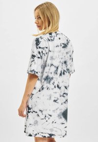 Kortärmad tie-dye klänning i svart och vitt, avslappnad passform med rund halsringning, mjukt tyg och en liten rund logotypdetalj på baksidan.